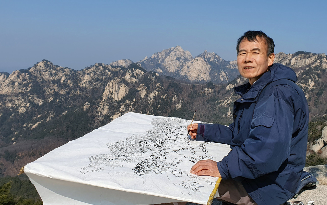 북한산 능선 바위에 앉아 그림을 그리는 김석환 건축사(사진=김석환 건축사)
